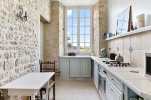 a kitchen with a stone wall and a stove top oven at Apartment in a 17th century Manoir - Chateau Isle Marie in Picauville