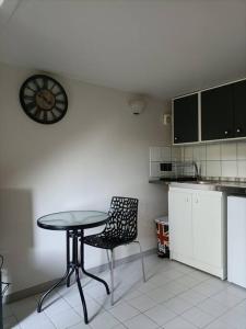 a kitchen with a table and a chair and a clock at Agréable et paisible studio in Franqueville-Saint-Pierre