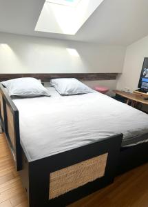Appartement au centre de Toulouse في تولوز: سرير كبير عليه أغطية ووسائد بيضاء