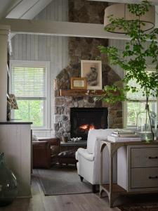 a living room with a stone fireplace and a white chair at Hidden Pond Resort in Kennebunkport