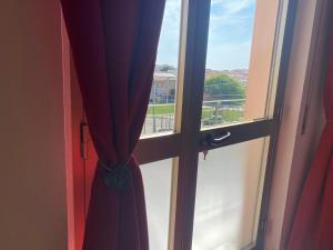 a window with a red curtain next to a door at Appartamento La Caletta in La Caletta