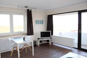 een woonkamer met een witte tafel en een televisie bij Germania-60 in Sankt Peter-Ording