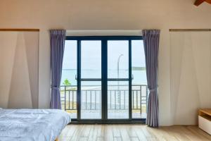 a bedroom with a large window with a view of the ocean at 澎湖奇遇菓海景民宿 in Xiyu