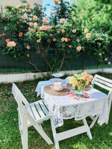 une table et des chaises blanches avec des fleurs. dans l'établissement La Casa della Rosa Nana, à Trezzano sul Naviglio