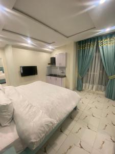 1 dormitorio con 1 cama blanca y TV en Luxe Suites Bahria Town Lahore en Lahore