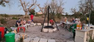 een groep mensen die aan tafels zitten rond een vuurplaats bij Camping Terreno-Ro-Bi-Li in Cutrofiano