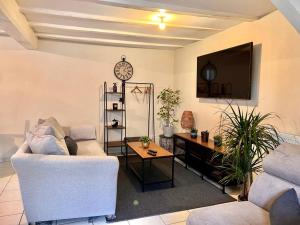 Maison avec terrasse cosy, 2 chambres, wifi, parking في Ruelle-sur-Touvre: غرفة معيشة مع أريكة وتلفزيون