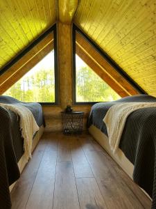 two beds in a room with two windows at Domek z bala MAZURY, bezpośredni dostęp do jeziora, plaża, pomost in Szczytno