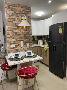 uma cozinha com um frigorífico preto e um balcão com cadeiras em Moderno Apto con vista panoramica a la ciudad a 5 min de la playa em Cartagena das Índias