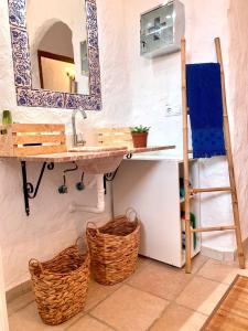 a bathroom with a sink and a mirror and baskets at Casa Cueva LA PARRA. in Terque