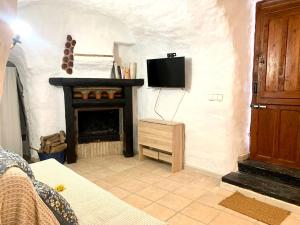 a living room with a tv and a fireplace at Casa Cueva LA PARRA. in Terque