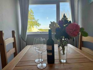 a bottle of wine and a vase of flowers on a wooden table at Faldouet 3 bed flat in Rock in Saint Minver