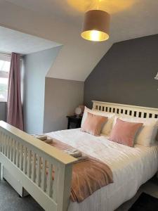a bedroom with a white bed with pink pillows at Faldouet 3 bed flat in Rock in Saint Minver