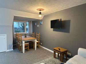 a dining room with a table and a tv on the wall at Faldouet 3 bed flat in Rock in Saint Minver