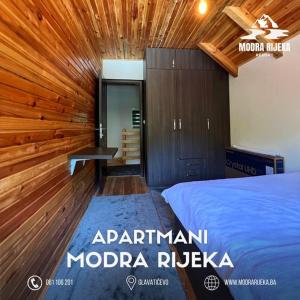 ein Schlafzimmer mit einem Bett und einer Holzwand in der Unterkunft Modra Rijeka Resort in Glavatičevo