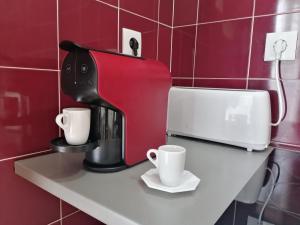 une cafetière et deux tasses sur une étagère dans l'établissement Hostel Rossio Alcobaça, à Alcobaça