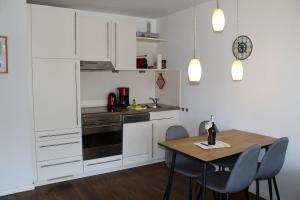 a kitchen with white cabinets and a table with chairs at Germania-30 in Böhl