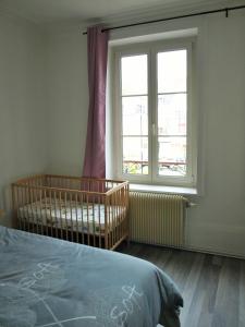 a bedroom with a crib and a large window at Sweethome-Epinal in Épinal