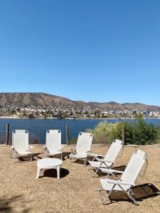a group of white chairs and a table and water at casas lago in Villa Carlos Paz