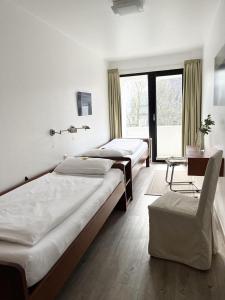 um quarto com 2 camas, uma cadeira e uma janela em Germania-34 em Sankt Peter-Ording