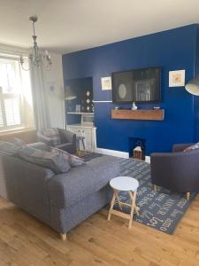een woonkamer met een grijze bank en een blauwe muur bij Beach Walk in Berwick-Upon-Tweed