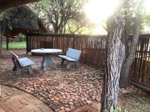 eine Terrasse mit einem Tisch, 2 Stühlen und einem Baum in der Unterkunft Munati B&B in Musina
