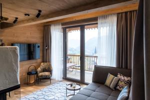 a living room with a couch and a balcony at Hideaway Hotel Montestyria Chalets & Suiten in Mariazell