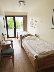 deux lits dans une chambre avec une chaise et une fenêtre dans l'établissement Germania-41, à Sankt Peter-Ording