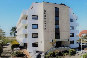 un grand bâtiment blanc avec une enseigne dessus dans l'établissement Germania-41, à Sankt Peter-Ording