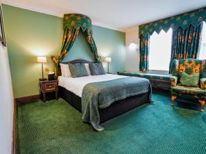a bedroom with a king sized bed and a chair at Villiers Hotel in Buckingham
