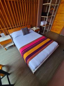 a bed with a colorful blanket on it in a room at Hotel Momotus in Tuxtla Gutiérrez
