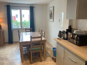 a kitchen with a wooden table and a dining room at Appartement neuf coeur du village in Saintes-Maries-de-la-Mer