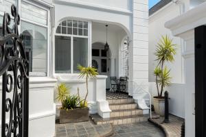 Cape Town的住宿－Neighbourgood Hill Suites，前廊上种有盆栽植物的白色房子