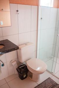 a bathroom with a toilet and a glass shower at Residencial Havaí in Guaratuba