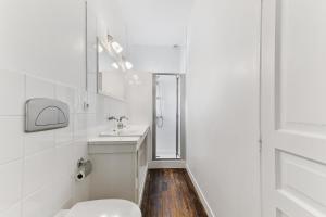 a white bathroom with a toilet and a sink at Apartment in a 17th century Manoir - Chateau Isle Marie in Picauville