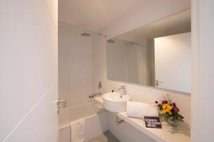 a white bathroom with a sink and a mirror at Top Rentals Brickell in Tigre