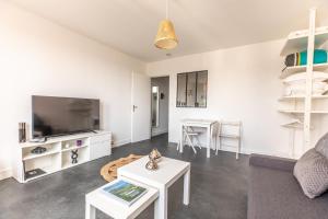 ein Wohnzimmer mit einem Sofa, einem TV und einem Tisch in der Unterkunft Studio Ernest Chamalières Calme Parking Gratuit in Chamalières