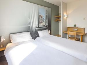 レンヌにあるB&B HOTEL Rennes Ouest Villejeanのテーブル付きの客室内の白いベッド2台