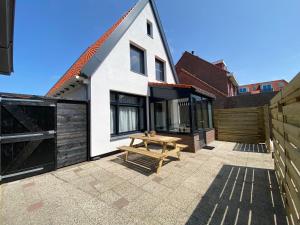 a white house with a wooden picnic table on a patio at The island life beach house 1 in De Koog