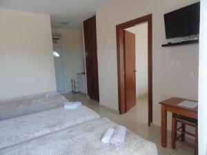 a room with two beds and a television and a table at Pension Delfini in Asprovalta