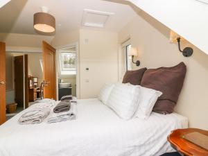 una camera da letto con letto, lenzuola e cuscini bianchi di Berg Cottage a Ballindalloch