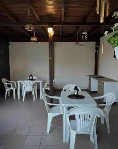 um restaurante com mesas brancas e cadeiras brancas em Pensiunea Dea House em Constança