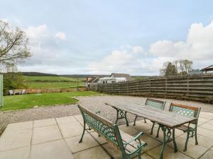 un tavolo da picnic in legno e 2 sedie su un patio di Berg Cottage a Ballindalloch