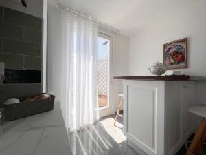 a white kitchen with a large window and a door at DC House in Procida