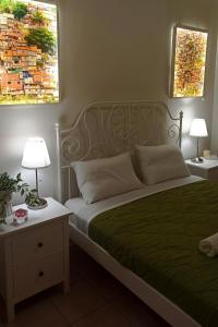 a bedroom with a bed with green sheets and two lamps at limonchello 2 in Kalamata