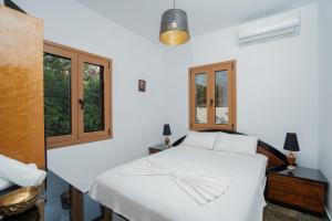 a bedroom with a white bed and two windows at Villa Beis in Porto Rafti