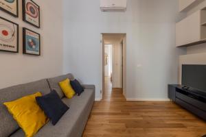 uma sala de estar com um sofá cinzento e almofadas amarelas em BnButler - Sebenico, 28 - Nuovissimo Appartamento in Isola em Milão