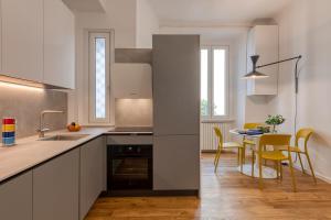 BnButler - Sebenico, 28 - Nuovissimo Appartamento in Isola في ميلانو: مطبخ مع دواليب بيضاء وطاولة مع كراسي صفراء