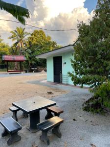 einem Picknicktisch und zwei Bänken vor einem Gebäude in der Unterkunft Mini Homestay Arifz Zai in Batu Kurau