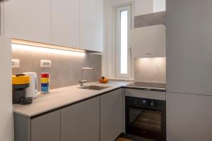 uma cozinha com armários brancos, um lavatório e uma janela em BnButler - Sebenico, 28 - Nuovissimo Appartamento in Isola em Milão